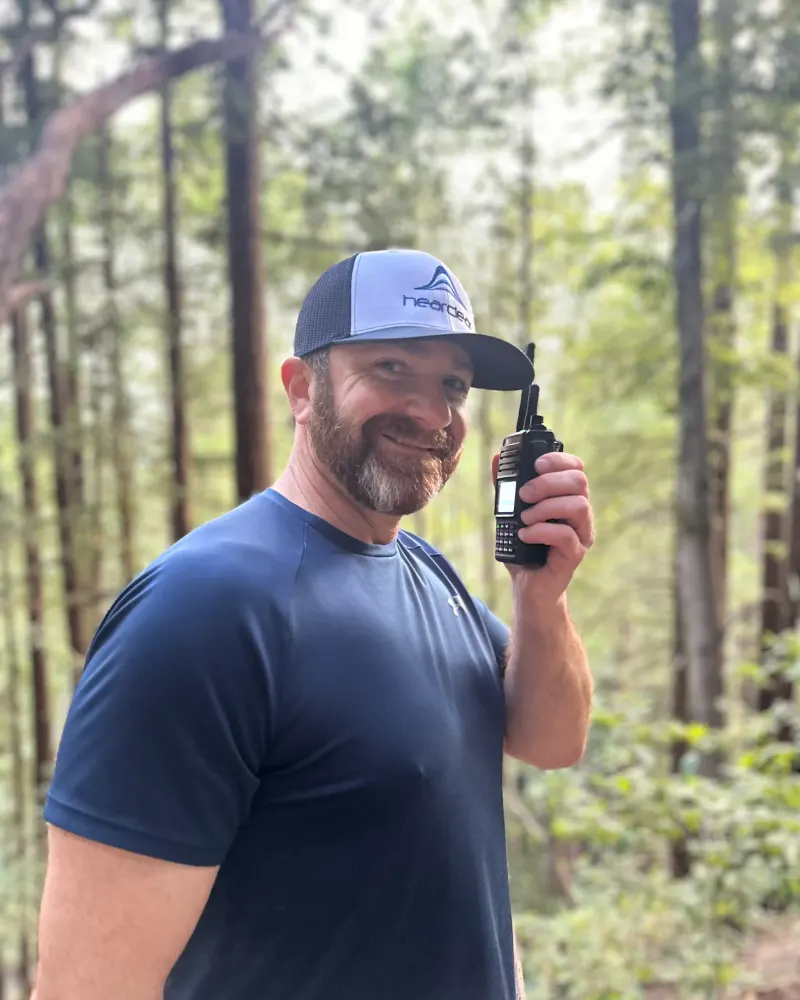 HearClear team member holding a HearClear push-to-talk radio outdoors